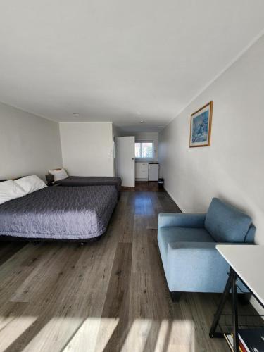 Gardena Court Motel في هاميلتون: غرفة نوم بسرير واريكة زرقاء