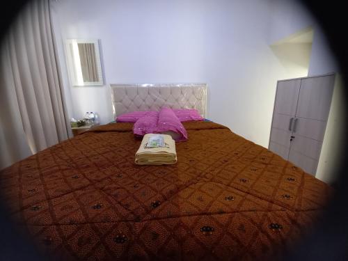 a bedroom with a bed with a blanket and purple pillows at BELLA NINE EXCLUSIVE HOMESTAY in Sukoharjo