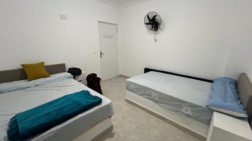 a small bedroom with two beds and a fan at New Chalet Sea & Pool view Ras Sedr شاليه جديد دور ارضي في راس سدر in Ras Sedr