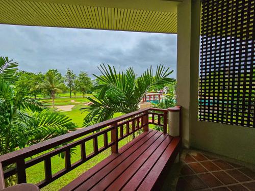 a balcony with a wooden deck with a view of a park at The Nouveau Chumphon Beach Resort And Golf in Chumphon