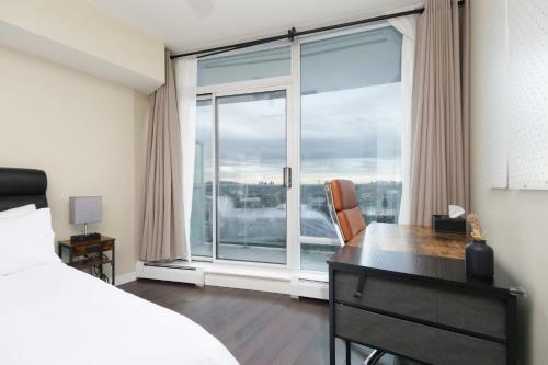 a bedroom with a desk and a large window at Sub-Penthouse Apartment with Jacuzzi Pool & Sauna in Vancouver