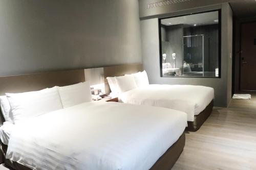 a hotel room with two beds and a mirror at Orient Luxury Hotel in Chiayi City