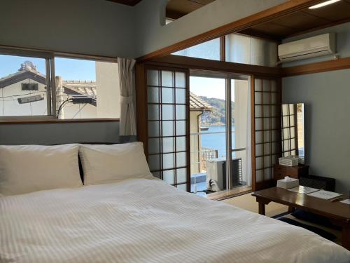 Un dormitorio con una cama y una ventana con vistas. en Oninosanpomichi, en Kumano