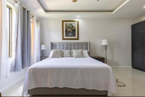 a bedroom with a large bed with white sheets at Luxury Palm in Old Harbour