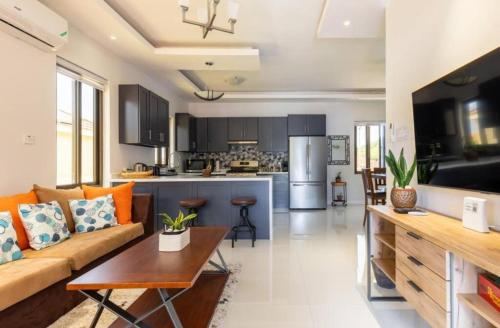 a living room with a couch and a kitchen at Luxury Palm in Old Harbour