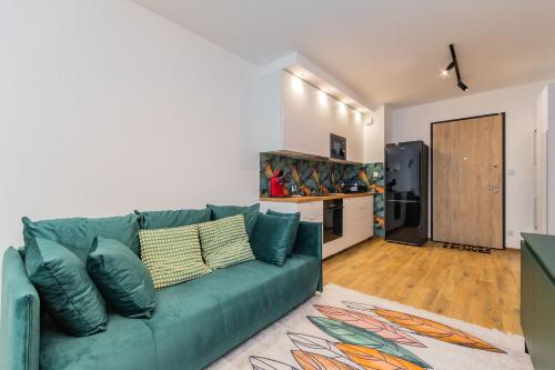 sala de estar con sofá verde y cocina en Letnica Jungle by Grand Apartments, en Gdansk