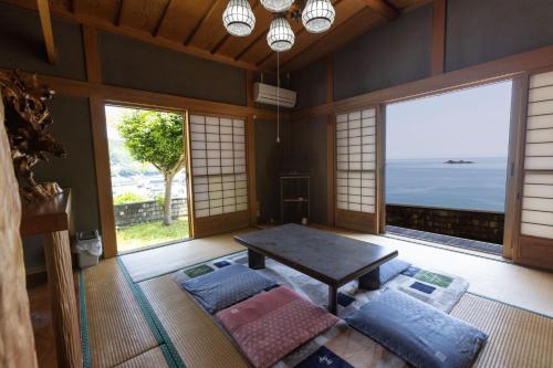 a living room with a table and a large window at Oninosanpomichi in Kumano