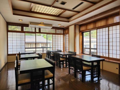 - une salle à manger avec des tables, des chaises et des fenêtres dans l'établissement 大和屋ホテルいろは, à Nikkō