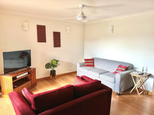 a living room with a couch and a tv at McKinnon on the Bay in East Ballina