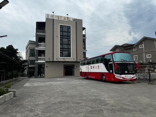 un autobús rojo y blanco estacionado frente a un edificio en 大衛營農莊 en Ch'ing-shui