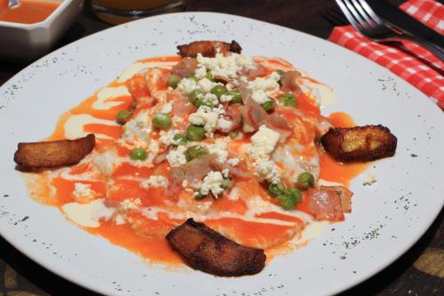 a white plate with a pizza with meat and cheese at HOTEL PLAZA SAN CRISTOBAL INN in San Cristóbal de Las Casas