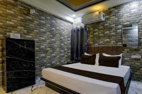 a bedroom with a bed and a brick wall at Collection O Hotel Leo Inn in Rajkot