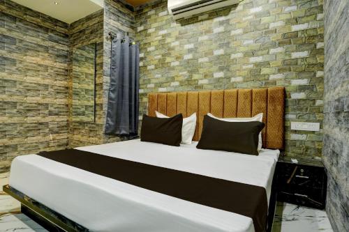 1 dormitorio con 1 cama grande y pared de ladrillo en Collection O Hotel Leo Inn, en Rajkot