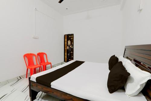 1 dormitorio con 1 cama y 2 sillas rojas en OYO RD PALACE, en Auraiya