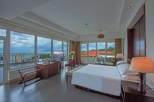 a bedroom with a large white bed and a balcony at Sheraton Huizhou Beach Resort in Huidong