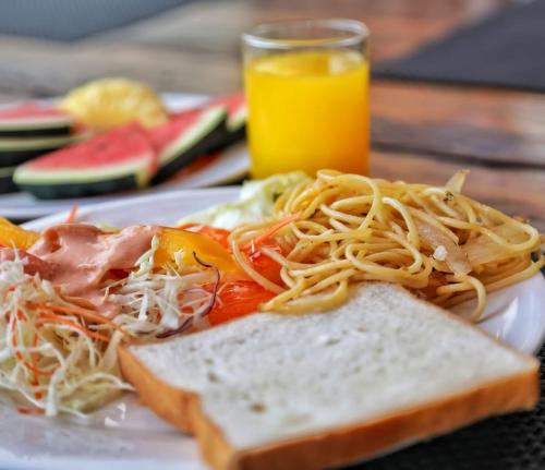a plate of food with spaghetti and bread and orange juice at Cokoon Deva Patong Hotel in Patong Beach