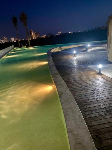 a swimming pool at night with lights on it at Departamento con Espectacular Alberca in Mazatlán