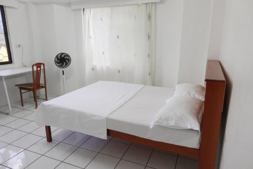 a bedroom with a bed with white sheets and a window at Nadi Bethel Homestay in Nadi