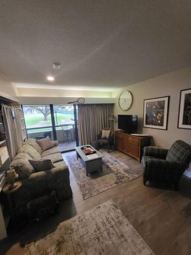 ein Wohnzimmer mit einem Sofa, einem Tisch und einer Uhr in der Unterkunft Palm Harbor Condo located within Innisbrook Golf Course in Palm Harbor