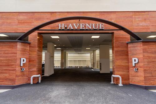 an entrance to a large building with a sign that reads havemite at H-avenue Hotel Munhyeon in Busan