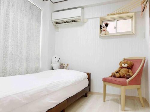 1 dormitorio con 1 cama y 1 silla con ositos de peluche en サカイマンション302, en Osaka