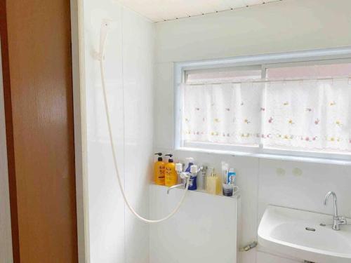 baño con ducha, lavabo y ventana en サカイマンション302, en Osaka