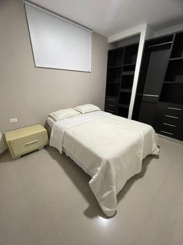 um quarto com uma cama branca e um projector em HERMOSO APARTAMENTO EN VALLEDUPAR em Valledupar