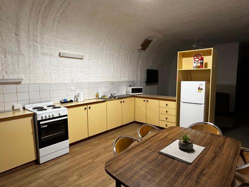 a kitchen with a table and a white refrigerator at Desert View Apartments in Coober Pedy