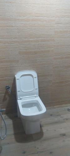 a white toilet in a room with a wooden wall at Tenam Garden homestay in Kalimpong