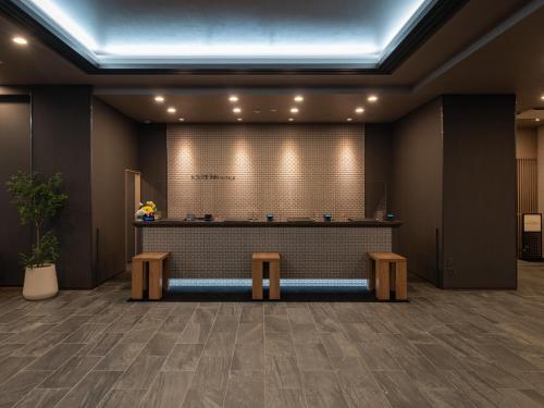 a lobby with a counter and two benches in a room at Hotel Route Inn Tokushima Airport -Matsushige Smartinter- in Matsushige