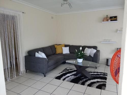a living room with a couch and a table at Olivia Pines Guesthouse 4 Bedroom Self Catering House in Krugersdorp