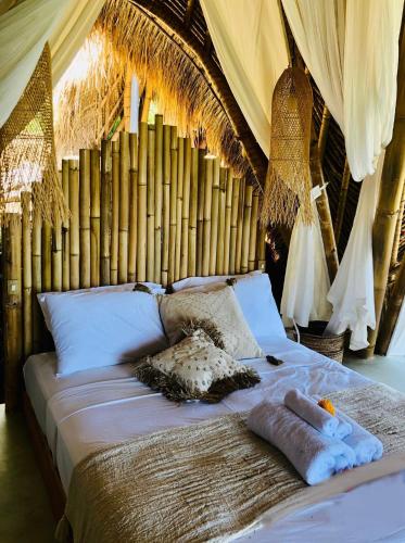 a large bed with white pillows andamboo at Bumi Cinta Bali in Tejakula