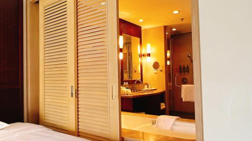 a bedroom with a bathroom with a tub and a sink at Sheraton Huizhou Beach Resort in Huidong