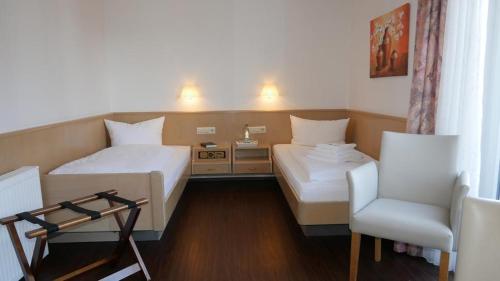 a hotel room with two beds and a chair at Hotel Garni Alte Post in Schallbach