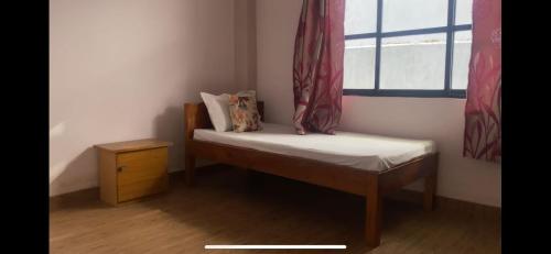 a small bed in a room with a window at Tenam Garden homestay in Kalimpong