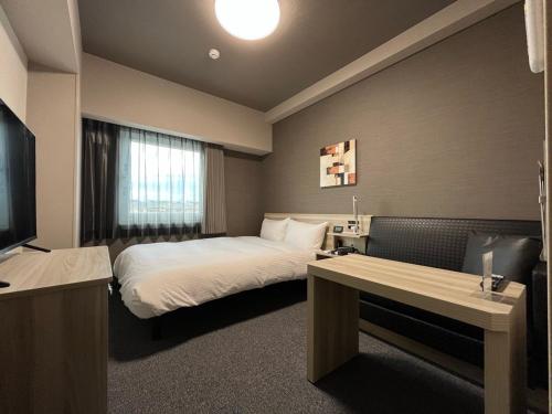 a hotel room with a bed and a television at Hotel Route Inn Tokushima Airport -Matsushige Smartinter- in Matsushige