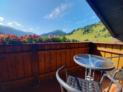 a table and chairs on a balcony with flowers at Ferienwohnungen Almsonne in Thomatal