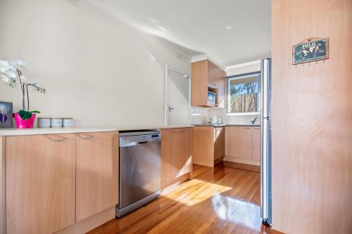 a kitchen with wooden cabinets and a stainless steel dishwasher at StayAU 2BRM Beach Family House Hampton in Melbourne