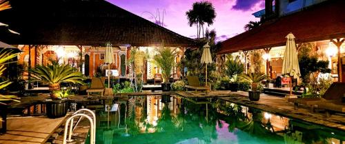 a swimming pool in front of a house at Stana Puri Gopa Hotel in Sanur