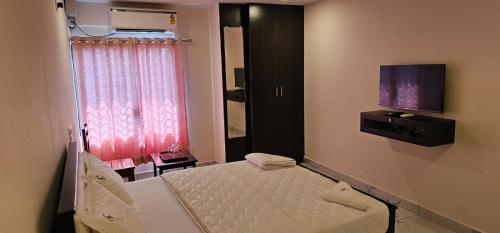 a bedroom with a bed and a tv on the wall at SAADHANA COMFORTS LODGE in Udupi