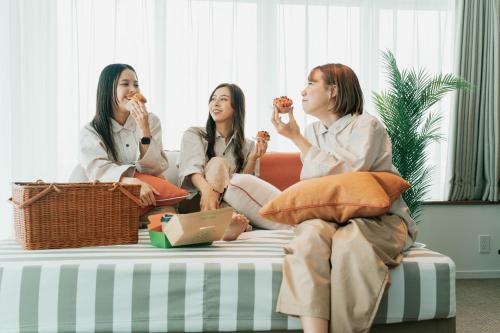 three women sitting on a bed eating food at THE SENAGAJIMA STORYLINE in Tomigusuku