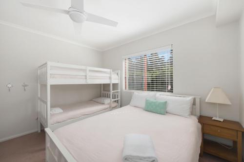a white bedroom with a bunk bed and a window at Fathoms 8 in Mollymook