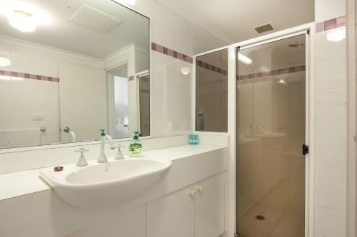a white bathroom with a sink and a shower at Fathoms 8 in Mollymook