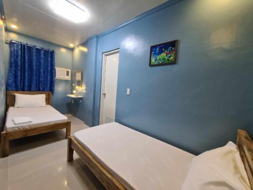 1 dormitorio con 2 camas y pared azul en Drossgold Pension House en Tubigon
