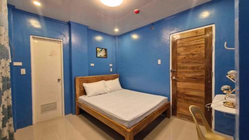 Habitación pequeña con cama y pared azul en Drossgold Pension House en Tubigon