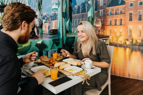 a man and woman sitting at a table eating breakfast at The Hague Teleport Hotel in The Hague