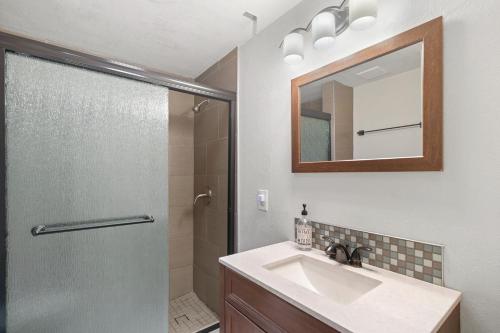 a bathroom with a sink and a shower with a mirror at The Cozy Cottage in Flagstaff