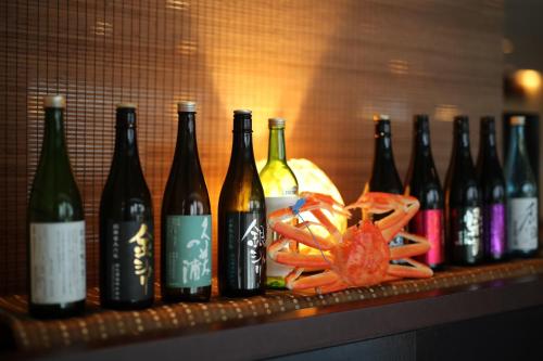 une rangée de bouteilles de vin et de crabe sur une étagère dans l'établissement Resorpia Kumihama, à Kyōtango
