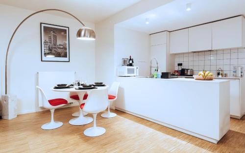 une cuisine avec un comptoir blanc, une table et des chaises dans l'établissement R213 Residences Botanique, à Bruxelles