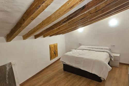 1 dormitorio con 1 cama en una habitación con techos de madera en El Capricho de San Andrés, en Calatayud